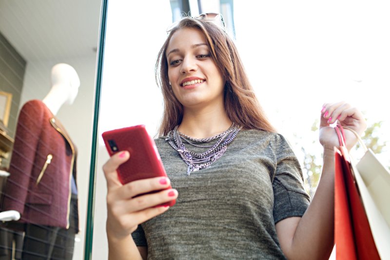 Lady in a shop checking prices on her mobile phone| Martec International